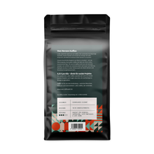 Laden Sie das Bild in den Galerie-Viewer, Rückseite der LUWU Marita Mild 1-kg-Kaffeepackung mit Qualitätsbeschreibung, Infos zur Langzeit-Trommelröstung, sozialem Engagement und Angaben zu Geschmack, Mischung und Röstgrad.